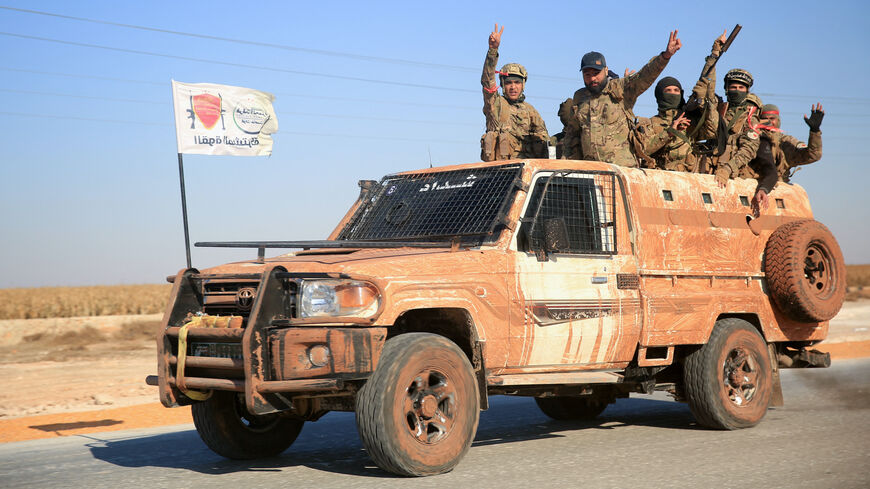 Anti-government fighters ride military vehicles as they drive along a road in the eastern part of Aleppo province on Dec. 1, 2024. 