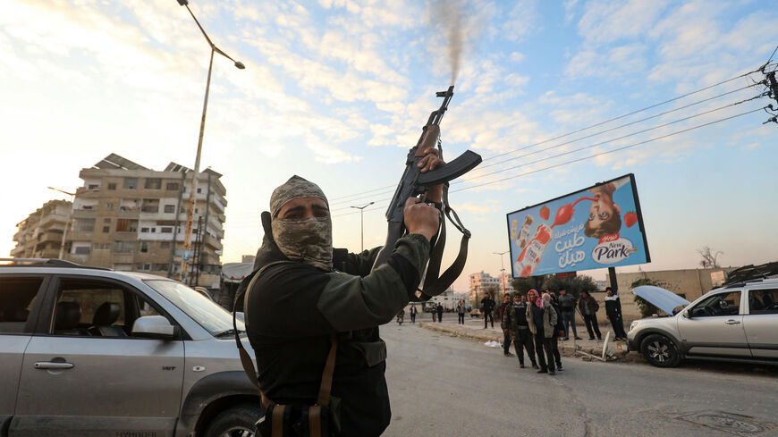 A Syrian anti government fighter fires his rifle into the air in the streets of the west-central city of Hama on Dec. 5, 2024.