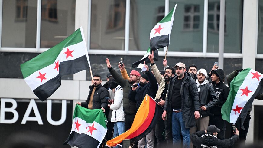 Members of the Syrian community in Berlin hold flags of Syria and Germany as they celebrate the collapse of Syrian President Bashar al-Assad's government, Dec. 8, 2024.