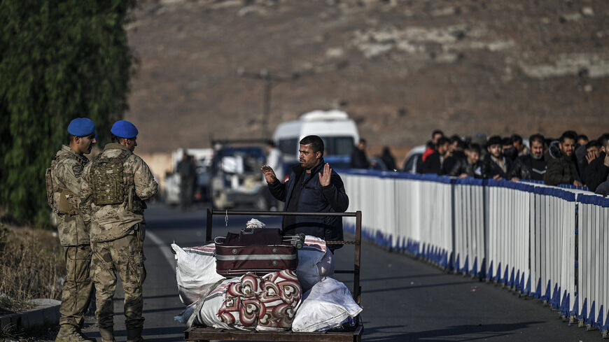 A Syrian refugee gestures as she speaks with Turkish soldiers at Cilvegozu crossborder gate before entering in Syria at Reyhanli district in Hatay, on December 9, 2024. Islamist-led rebels declared on December 8, 2024, that they have taken the Syrian capital in a lightning offensive, sending President Bashar al-Assad fleeing and ending five decades of Baath rule in Syria. (Photo by Ozan KOSE / AFP) (Photo by OZAN KOSE/AFP via Getty Images)