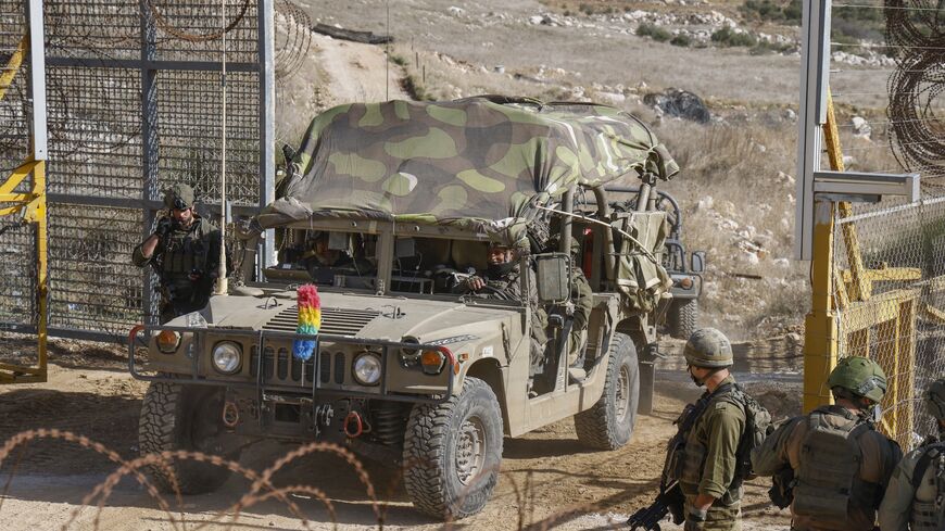 Israeli military vehicles cross the fence as they return from the buffer zone with Syria.