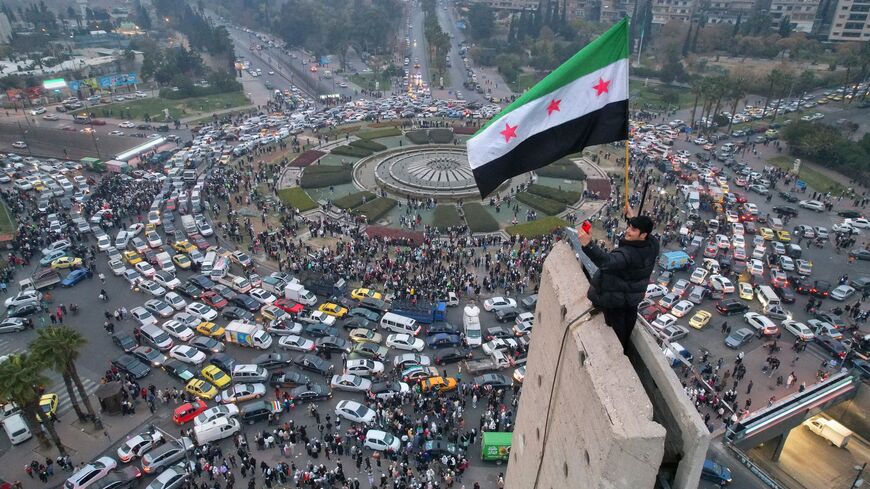 An aerial view shows a Syrian man waving the independence-era Syrian flag at Damascus' central Umayyad Square, on Dec. 11, 2024. 