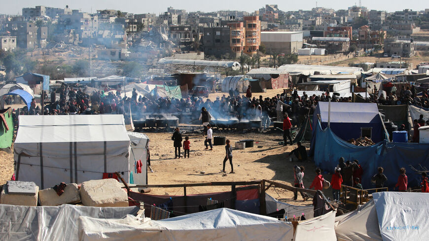 Palestinians stand in wait for a food portion at a distribution centre south of Khan Yunis in the southern Gaza Strip on December 17, 2024, amid the ongoing war between Israel and the Palestinian Hamas movement. (Photo by BASHAR TALEB / AFP) (Photo by BASHAR TALEB/AFP via Getty Images)