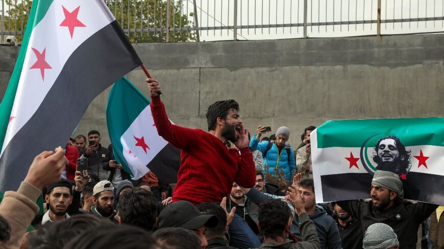 Syrians wave opposition flags, one with the portrait of late rebel fighter Abdel-Basset al-Sarout in Arbil, in the capital of Iraq's northern autonomous Kurdish region, after rebels captured the Syrian capital