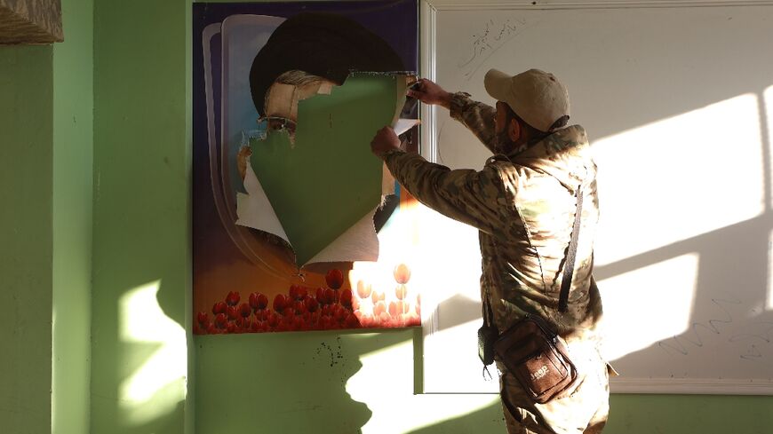 A fighter rips a portrait of slain Hezbollah leader Hassan Nasrallah, in a building in Qusayr