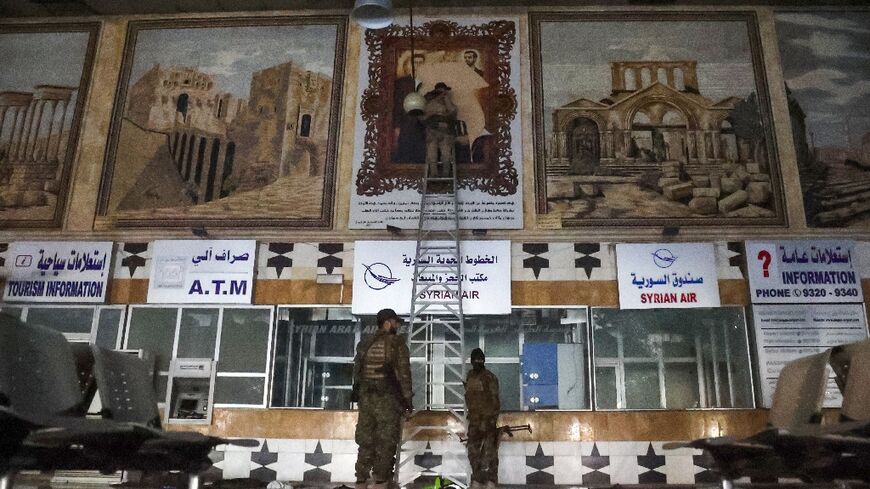 Anti-regime fighters tear off a poster depicting Syrian President Bachar al-Assad and his brother Maher at the airport in the northern Syrian city of Aleppo