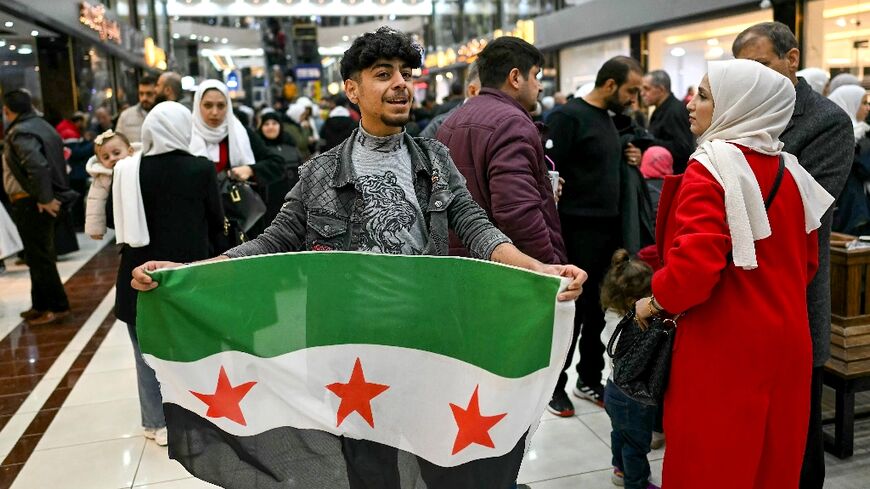 A young man holds a Syrian independence flag in a shopping mall near Sarmada, in the northern province of Idlib