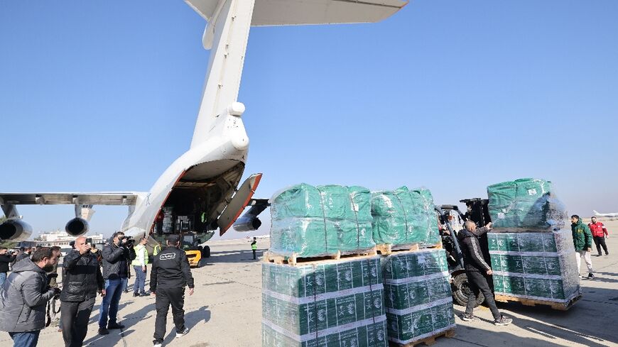 Workers unload humanitarian aid supplied by Saudi Arabia at the airport in Damascus; a high-ranking Syrian delegation has traveled to Saudi Arabia on the first foreign visit by the country's new Islamist rulers 