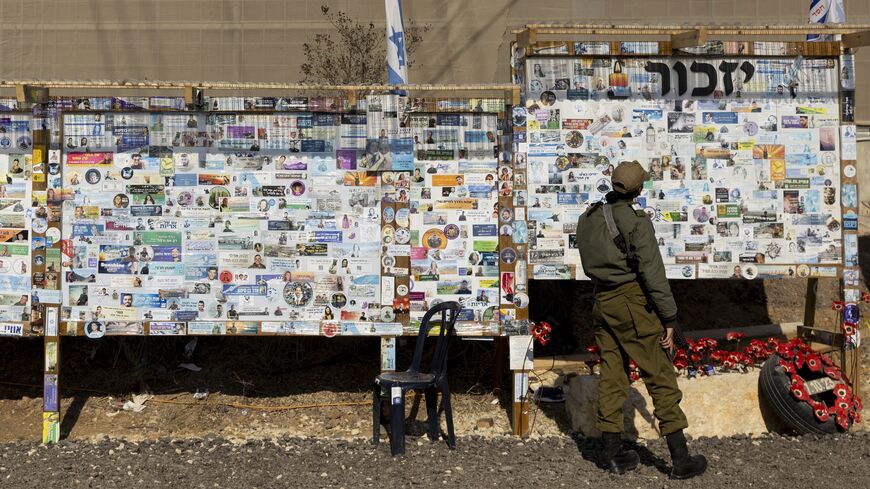 An Israeli soldier looks at a memorial wall for Israeli people and soldiers who were killed since the Oct. 7 deadly Hamas attack.