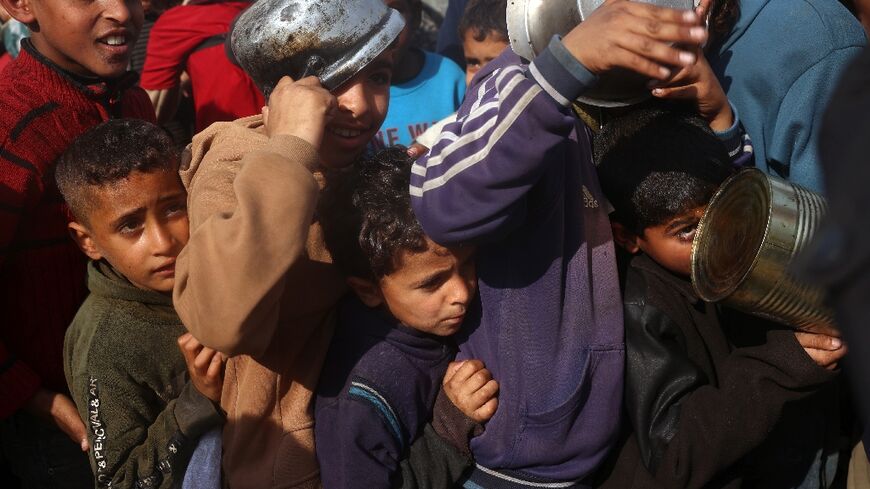 Palestinian children queue for food aid in central Gaza's Deir al-Balah, following the announcement of the truce