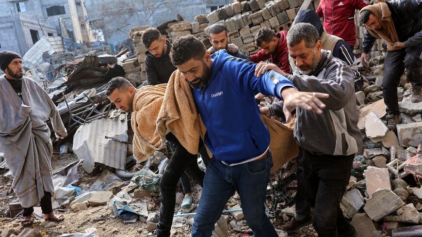 Palestinians carry a body after, according to Civil Defence rescuers, an Israeli strike on the al-Ghoula family home in the Gaza City area