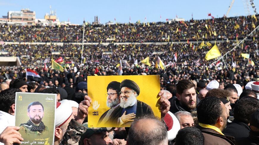 A mourner carries the portraits of Hezbollah's slain leader Hassan Nasrallah and Hashem Safieddine during their funeral