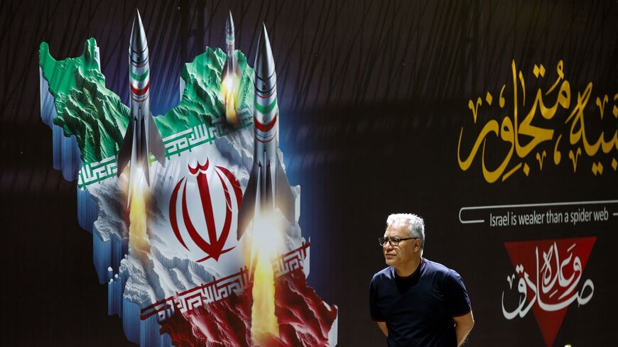 A man walks past a banner depicting missiles along a street in Tehran on April 19, 2024.