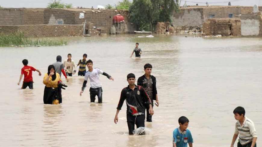 People cross a flooded area in Sheikh Saad district, south Baghdad, May 6, 2013. Heavy rains flood villages in southeastern Iraq forcing people to evacuate their homes as waves of water covered streets and houses. Picture taken May 6, 2013. REUTERS/Jaafer Abed (IRAQ - Tags: ENVIRONMENT) - RTXZDIR