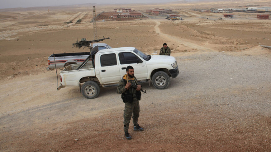 Forces loyal to Syria's President Bashar al-Assad stand beside a military vehicle in Mahr and Shaer gas fields after regaining control of the area, in Homs countryside November 15, 2014. REUTERS/George Ourfalian (SYRIA - Tags: POLITICS CIVIL UNREST CONFLICT MILITARY) - RTR4EA4N