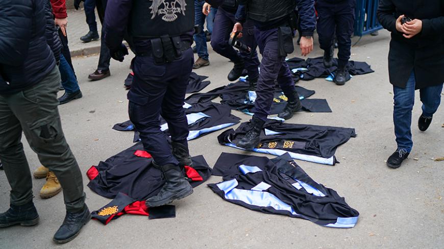 Riot policemen walk over gowns which were laid down by academics during a protest against the dismissal of academics from universities following a post-coup emergency decree, in the Cebeci campus of Ankara University in Ankara, Turkey, February 10, 2017. REUTERS/Umit Bektas - RTX30F6V