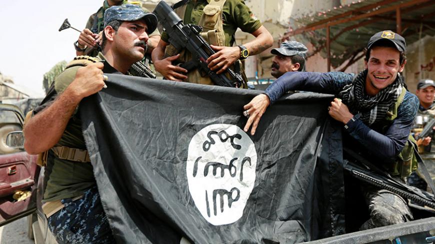 Iraqi Federal Police members hold an Islamic State flag, which they pulled down during fighting between Iraqi forces and Islamic State militants, in the Old City of Mosul, Iraq July 4, 2017. REUTERS/Ahmed Saad - RTX3A0D3