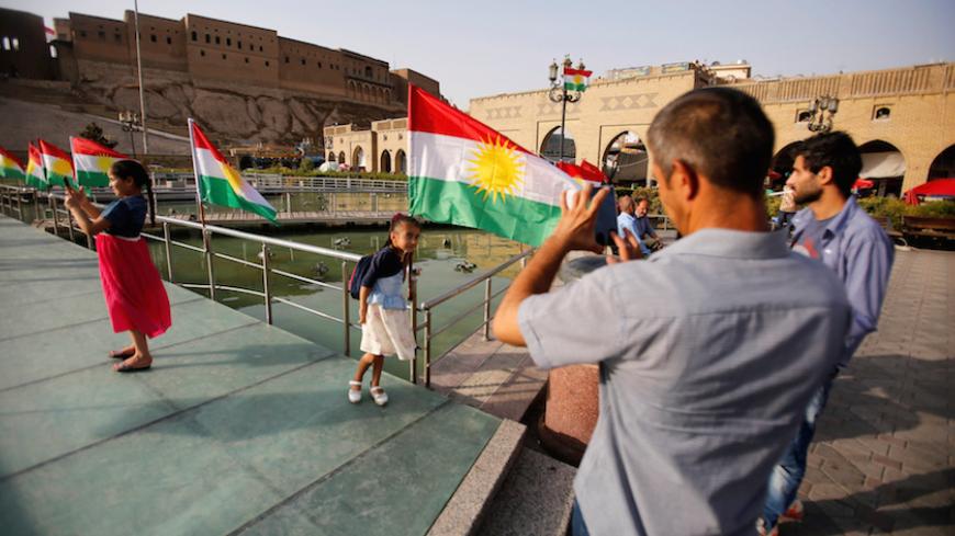 A man takes a picture of his daugther near the Kurdistan flag at the castle of Erbil, Iraq, July 29,2017. REUTERS/Khalid Al-Mousily - RTS19OL9