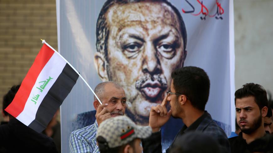 Iraqis, one with a national flag, stand in front of a banner bearing a portrait of Turkish President Recep Tayyip Erdogan during a demonstration to demand the withdrawal of the Turkish troops from the Bashiqa camp, located in the Mosul province, on October 8, 2016 outside the Turkish Embassy in Baghdad.
Turkey said on October 6, 2016 that its troops will remain in Iraq despite Baghdad's growing anger ahead of a planned operation to retake the Iraqi city of Mosul from Islamic State group jihadists. Turkey ha