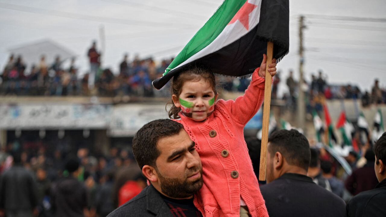A girl holds a Syrian opposition flag during a demonstration in the village of Atme in Idlib.