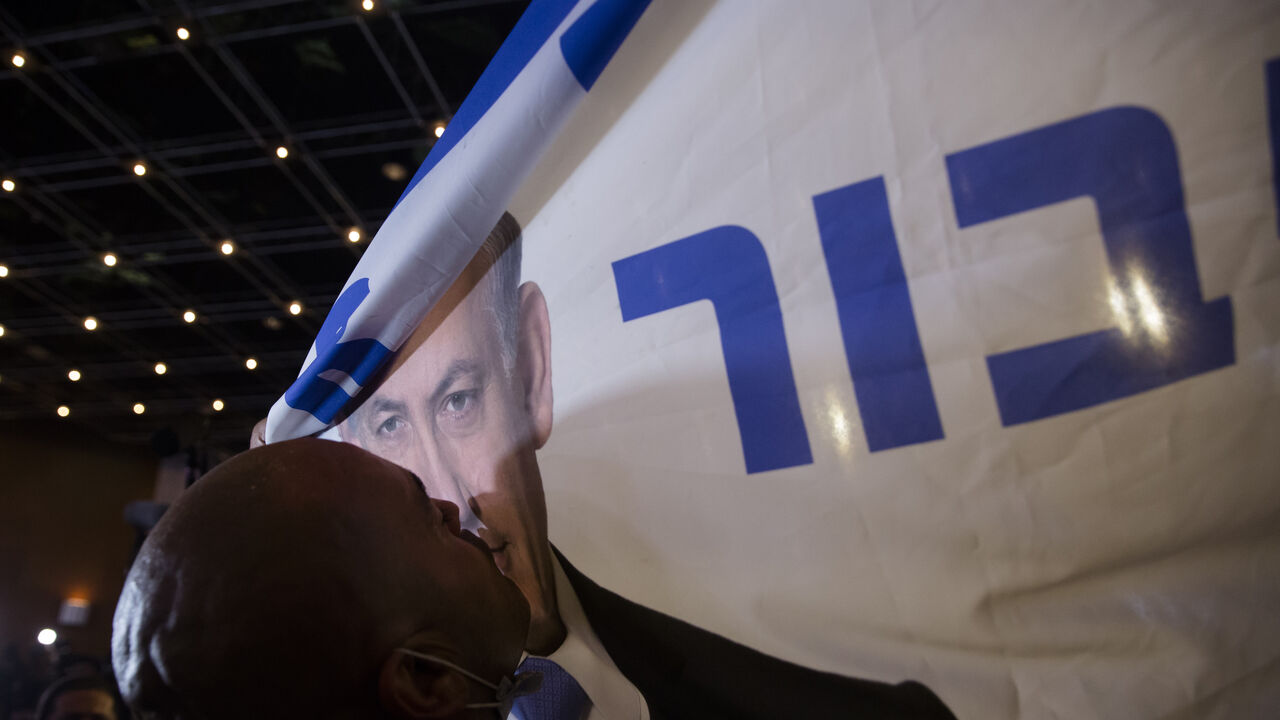 A Likud party supporter kisses a flag with a photo of Israeli Prime Minister Benjamin Netanyahu after the exit polls on March 23, 2021 in Jerusalem, Israel. 