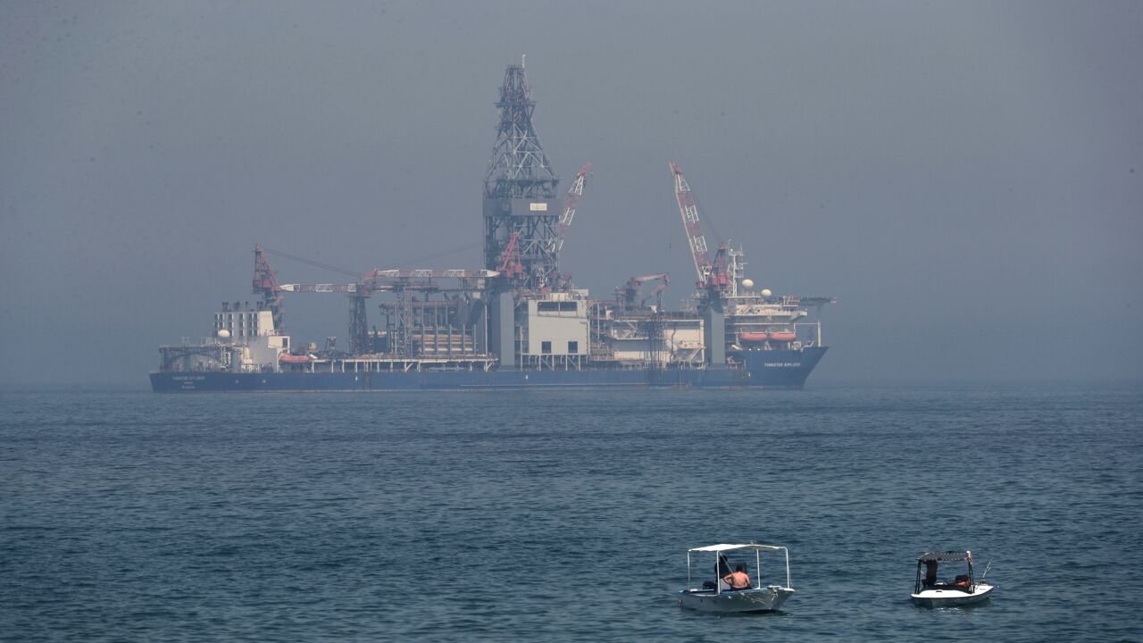 Lebanese people sit in boats in the Mediterranean Sea as the Tungsten Explorer, a drillship to explore for oil and gas off the coast of Lebanon, is seen in the background in Dbayeh north of the capital, Beirut, on May 15, 2020.