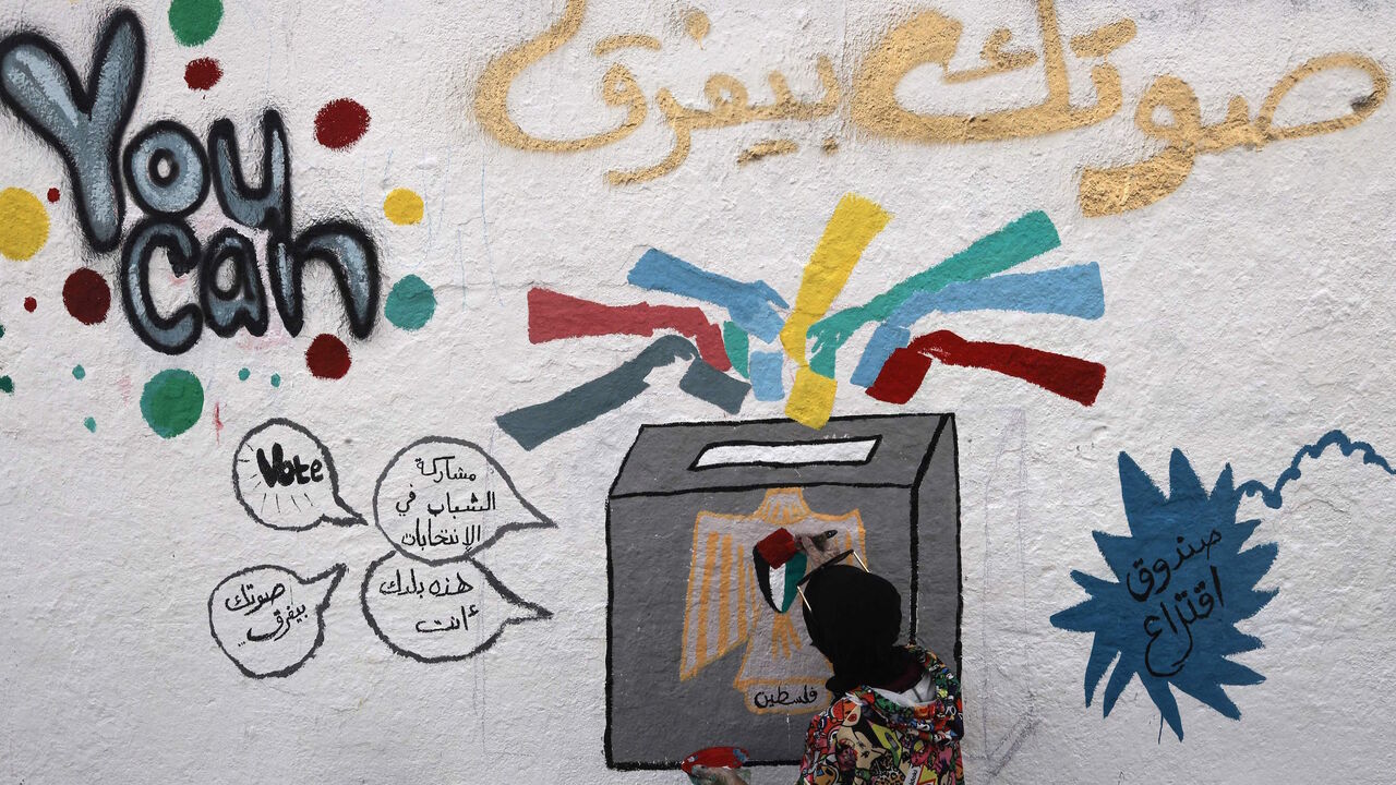 A Palestinian artist adds the final touches to a mural painting calling on people to vote during the upcoming elections (legislative in May and presidential in July) in a street in Gaza City, on March 24, 2021.