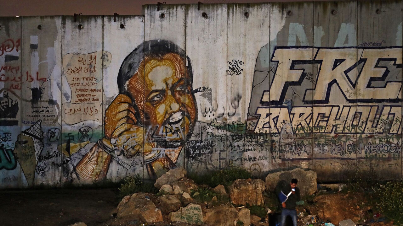 A picture taken on March 31, 2021 near the Israeli Qalandiya checkpoint, between Jerusalem and Ramallah, shows a mural of Fatah leader Marwan Barghuti on a section of Israel's controversial separation wall. - Imprisoned Palestinian leader Marwan Barghouti has endorsed a list of challengers opposing president Mahmud Abbas's Fatah movement in legislative elections next month, the head of the dissident list said on April 1. (Photo by Ahmad GHARABLI / AFP) (Photo by AHMAD GHARABLI/AFP via Getty Images)