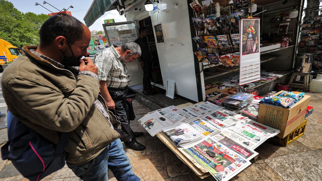 Men view the covers of local newspapers laid out at a stall in the Shemiran district of Iran's capital, Tehran, on April 14, 2021. Iran warned it would start enriching uranium up to 60% purity after an explosion it blamed on archenemy Israel hit its key nuclear facility in Natanz.