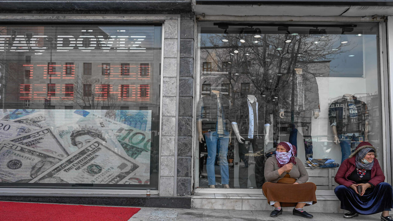 Women sit next to an exchange office at Laleli in Istanbul, Turkey, March 22, 2021.