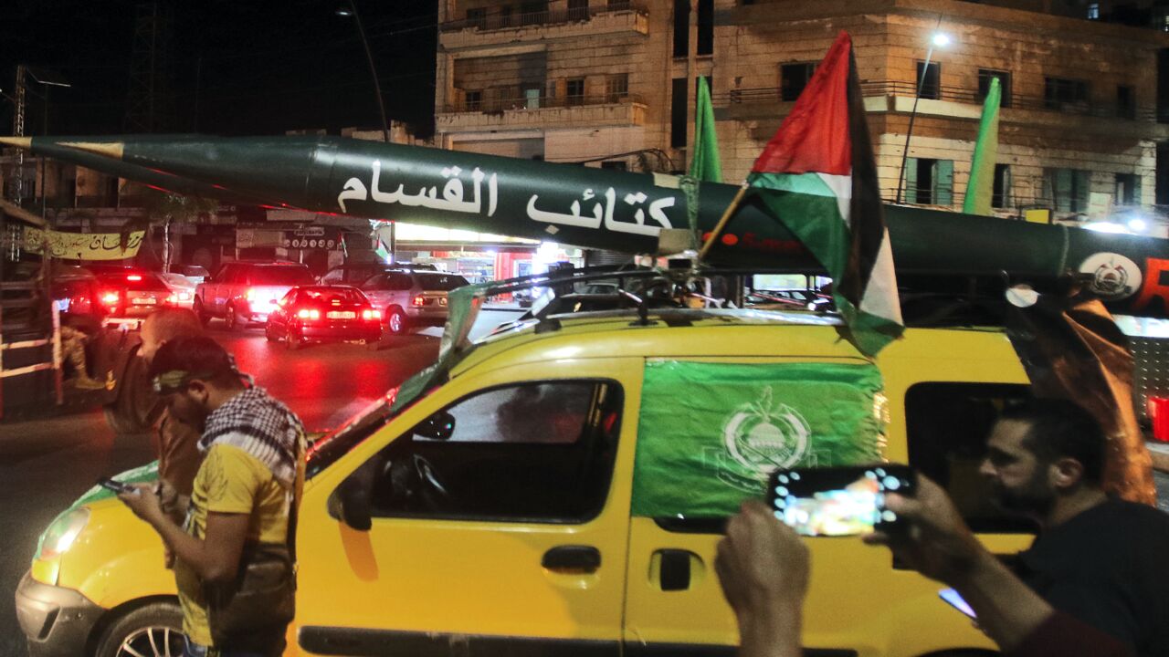 Men parade with a model of a rocket with "Qassam Brigades" (Hamas armed wing) written in Arabic, during a demonstration called by the Palestinian Islamist group Hamas in the southern Lebanese city of Saida late on May 11, 2021.