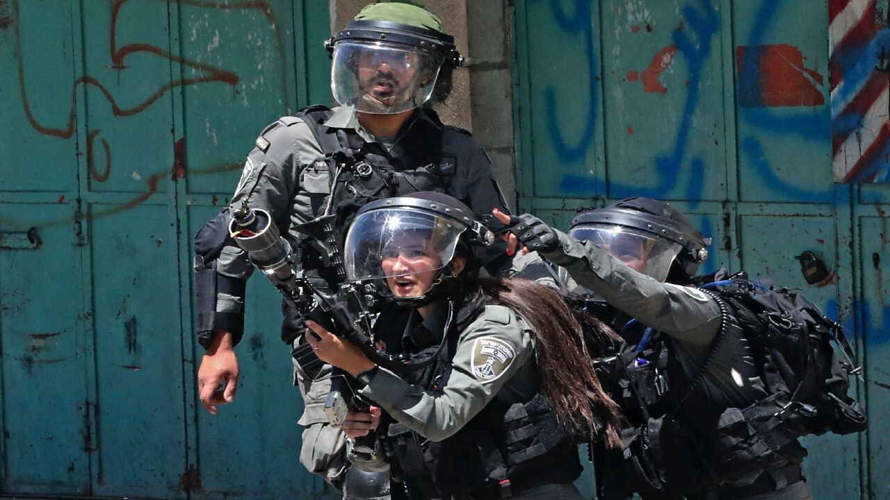 A member of the Israeli security forces fires tear gas at Palestinian protesters, during confrontations with them in the occupied West Bank city of Hebron, on May 14, 2021.