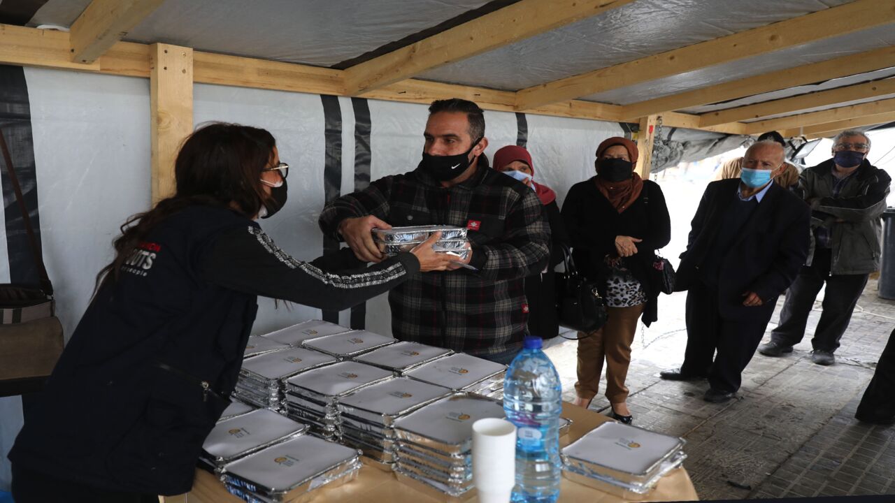 A volunteer gives out food handouts to people in need at the Lebanese grassroots organization in Beirut's Mar Mikhael district, which was hard hit by last year's port explosion, on March 24, 2021. 