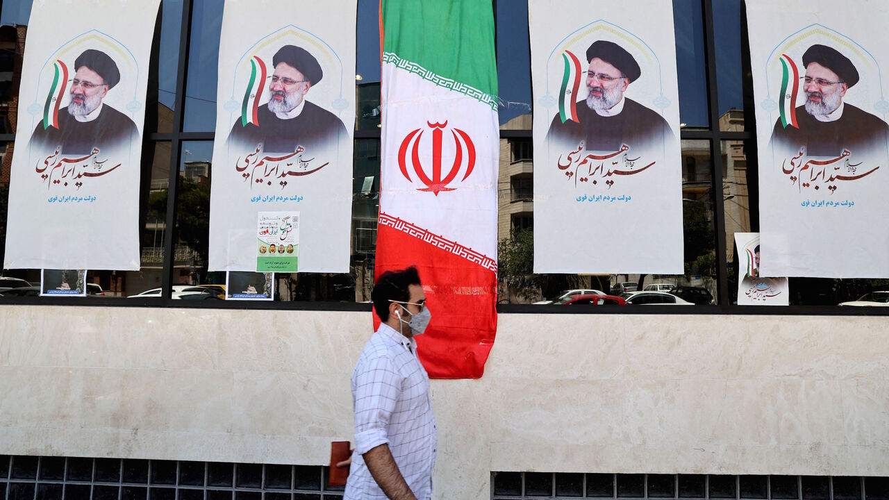 An Iranian man walks by posters of presidential candidate Ebrahim Raisi outside a campaign office in Tehran on June 7, 2021. 