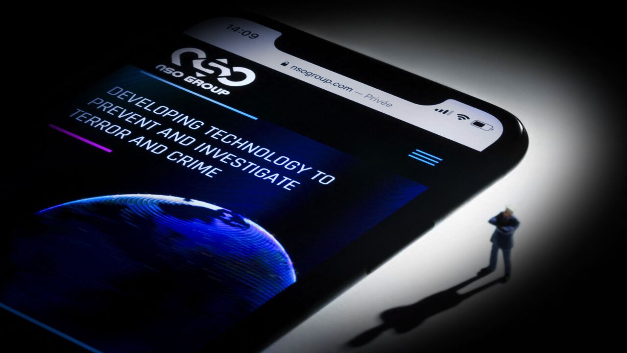 This studio photographic illustration shows a smartphone with the website of Israel's NSO Group.