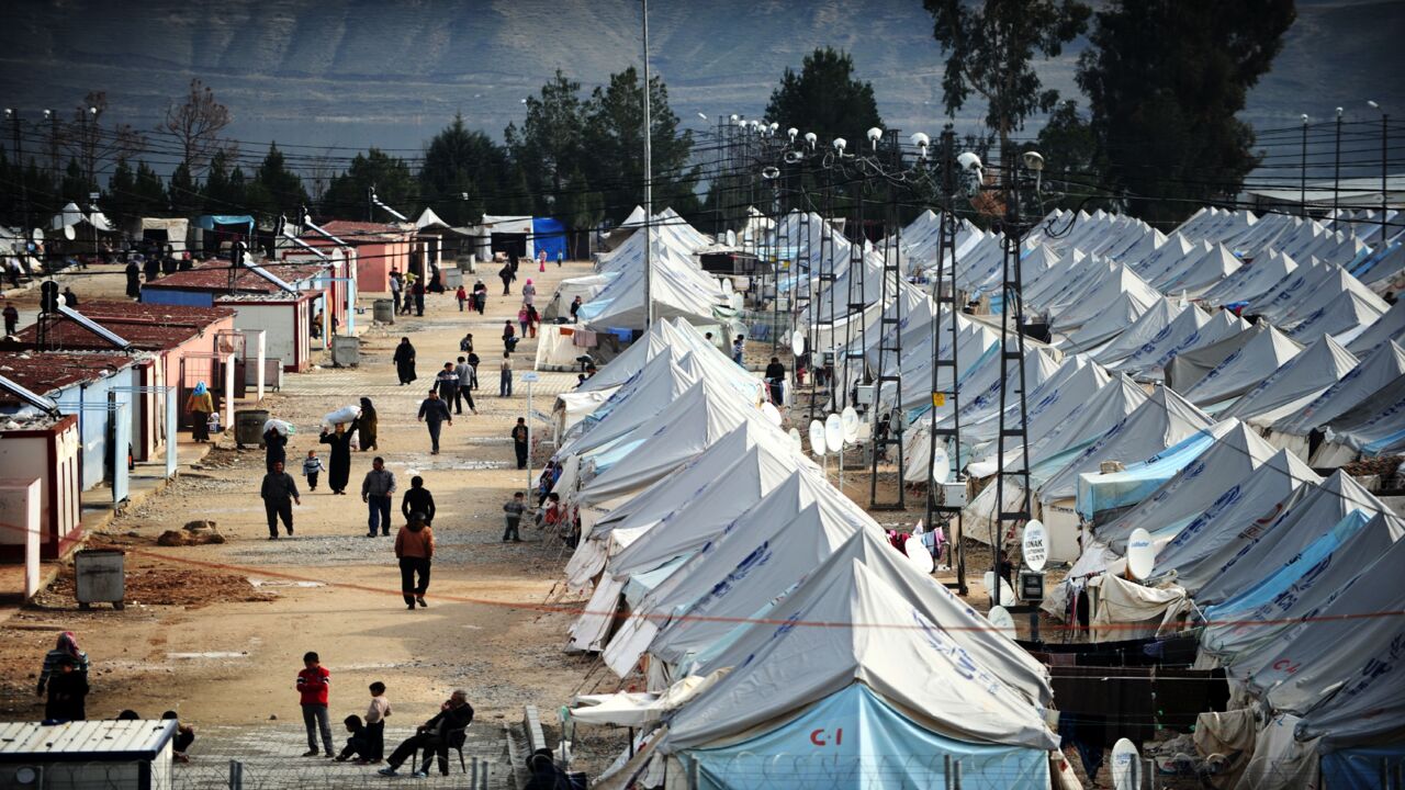 Syrian refugees walk among tents at Karkamis' refugee camp on January 16, 2014, near the town of Gaziantep, south of Turkey.