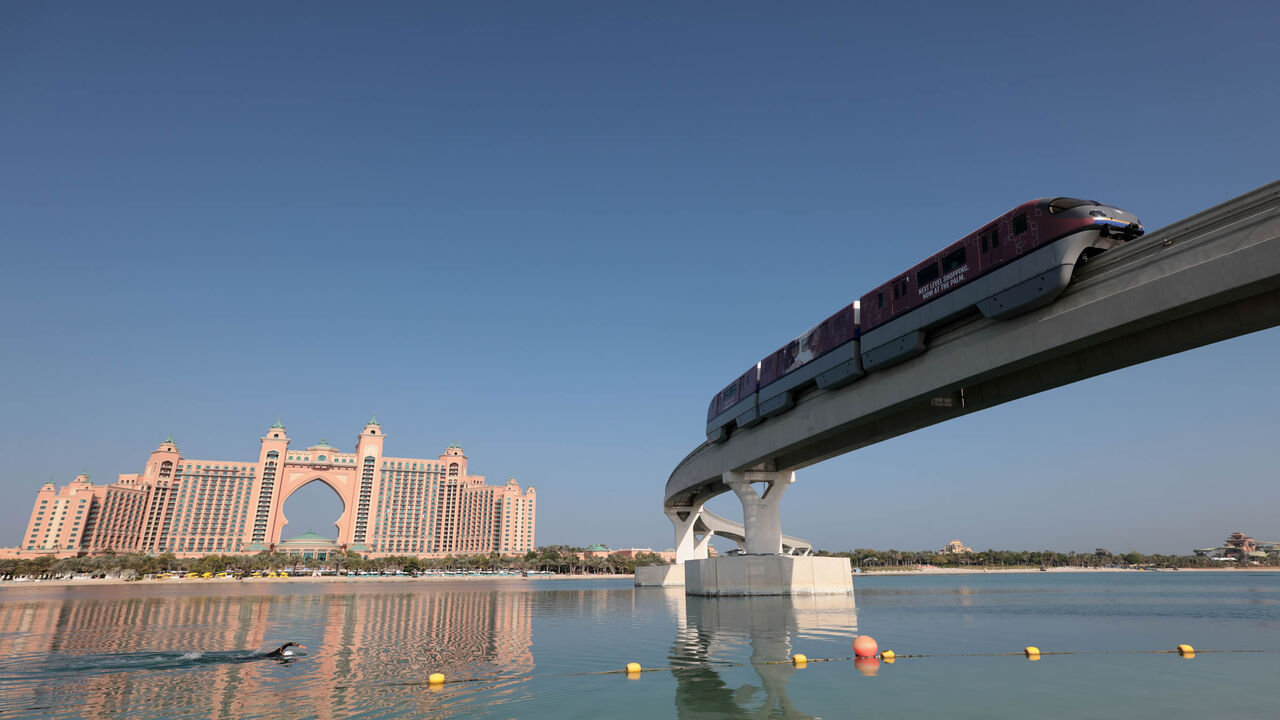 A man swims near a section of the Palm Jumeirah monorail, with the Atlantis Hotel in the background, Dubai, United Arab Emirates, Nov. 16, 2020.