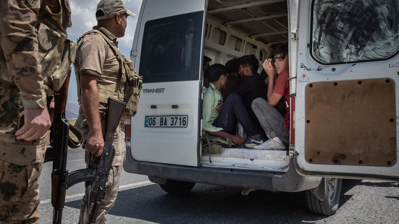 Jandarma officers monitor Afghan migrants sitting in the back of a smuggler's van that was caught transporting the migrants from the Turkey-Iran border on July 10, 2021 in Caldiran, Turkey.