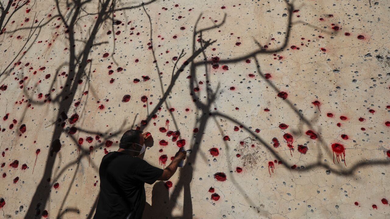 An Iranian Kurdish peshmerga member of the Kurdistan Democratic Party of Iran (KDPI) sprays red paint on holes in a wall made by shrapnel from a rocket attack days earlier.