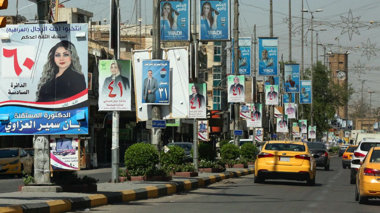 Iraqis go about their day beneath electoral billboards and placards of candidates for the upcoming parliamentary elections, in the district of Adhamiyah in the capital, Baghdad, on Sept. 17, 2021.