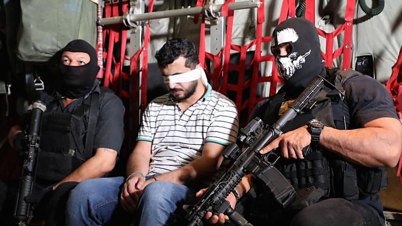 A handout picture provided by Iraq's army spokesman Yahya Rasool's official Twitter account on Oct. 18, 2021 reportedly shows blindfolded Ghazwan Alzawbaee, the suspect behind a 2016 attack claimed by the Islamic State group that killed more than 320 in Baghdad, flanked by two armed men at un undisclosed location. 