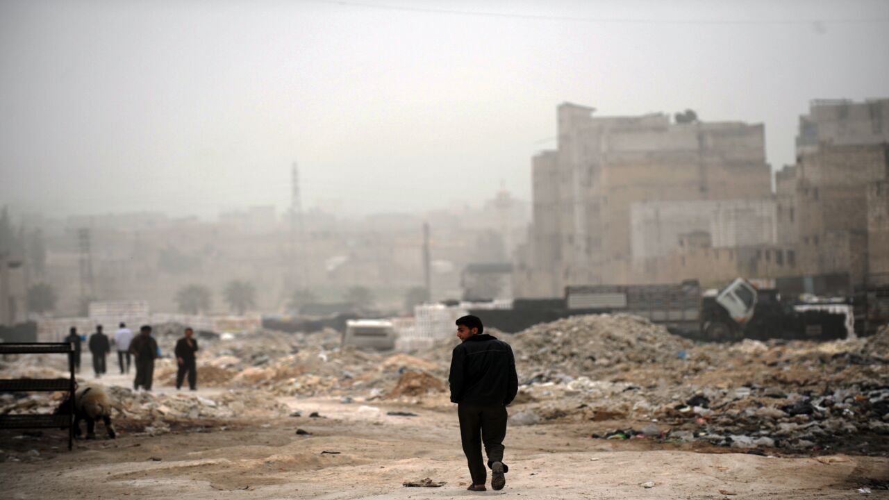 A Syrian man walks past destruction in the northern city of Aleppo on March 22, 2013.