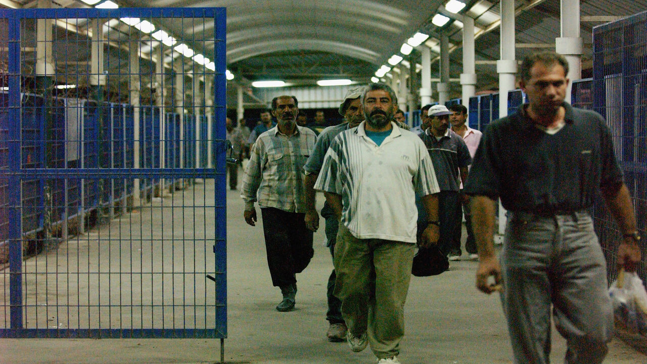 Palestinian workers cross into Israel from the Gaza Strip at the Erez border crossing point, Israel, Sept. 24, 2003.