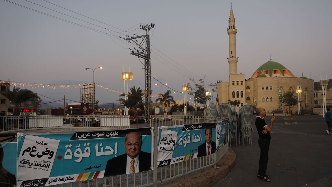 A pedestrian walks past electoral posters in the northern Arab-Israeli town of Sakhnin on Sept. 15, 2019, two days ahead of the Israeli general elections.