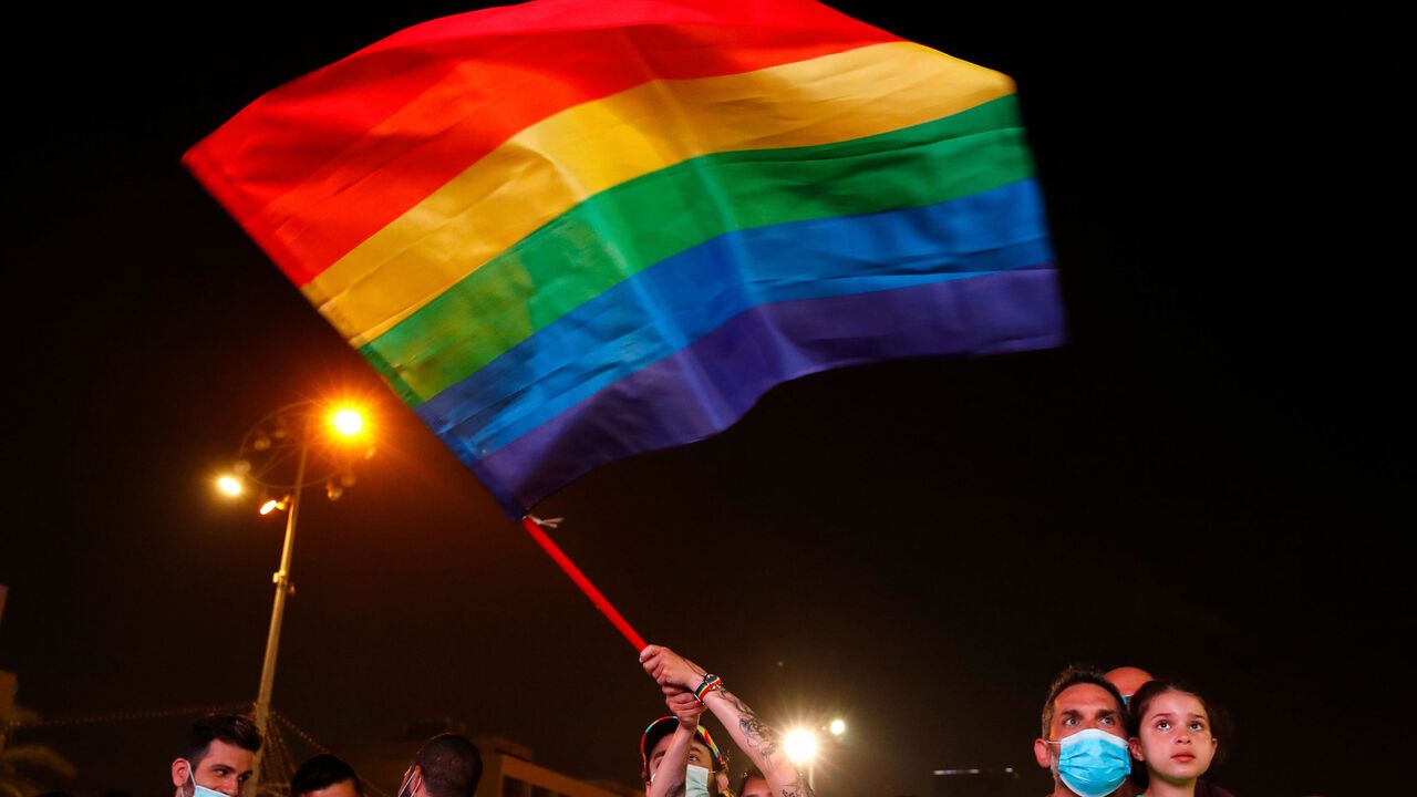 A mask-clad participant waves the LGBTQ rainbow flag as she takes part in Tel Aviv's annual Pride Parade amid the COVID-19 pandemic, on June 28, 2020. 