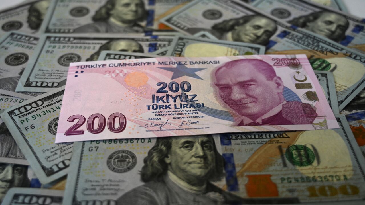 A picture taken on Dec. 7, 2021, in Istanbul shows US dollars banknotes and Turkish lira banknotes. 