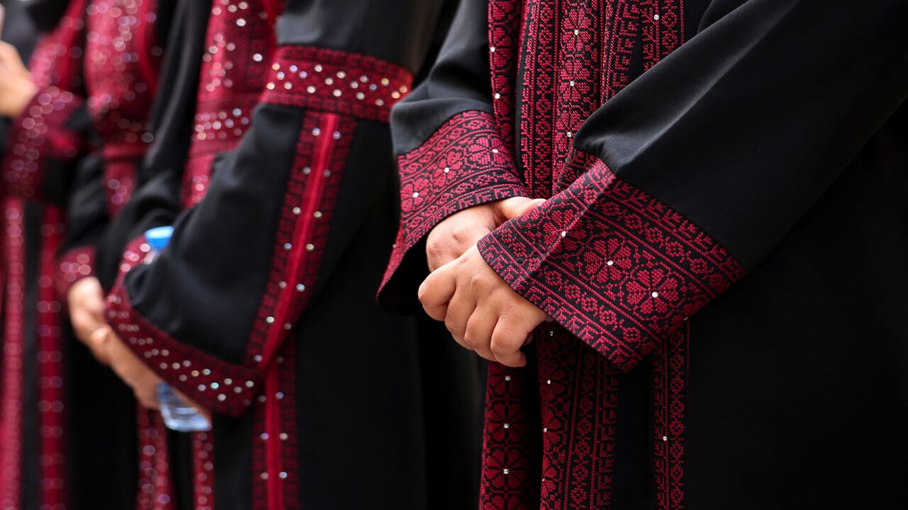 Palestinian university students wearing traditional embroidered dresses take part in an event entitled "Don't Steal Our Heritage" in Gaza City, on Dec. 16, 2021.  