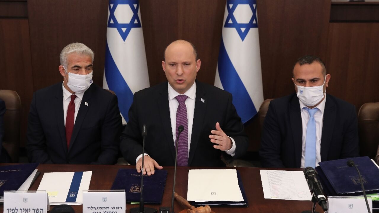 Israeli Prime Minister Naftali Bennett, in the centre,  Foreign Minister Yair Lapid, on the left, and Government Secretary Shalom Shlomo attend a cabinet meeting in Jerusalem on February 27, 2022