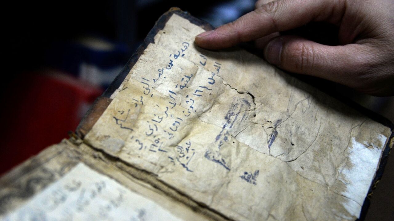 A librarian shows a book from University of Iraq's northern city of Mosul, one of those that escaped destruction at the hands of the Islamic State group