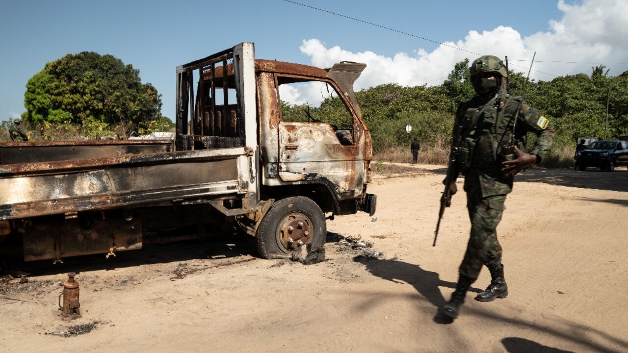 A Rwandan soldier walks in front of a burned-out truck near Palma last September